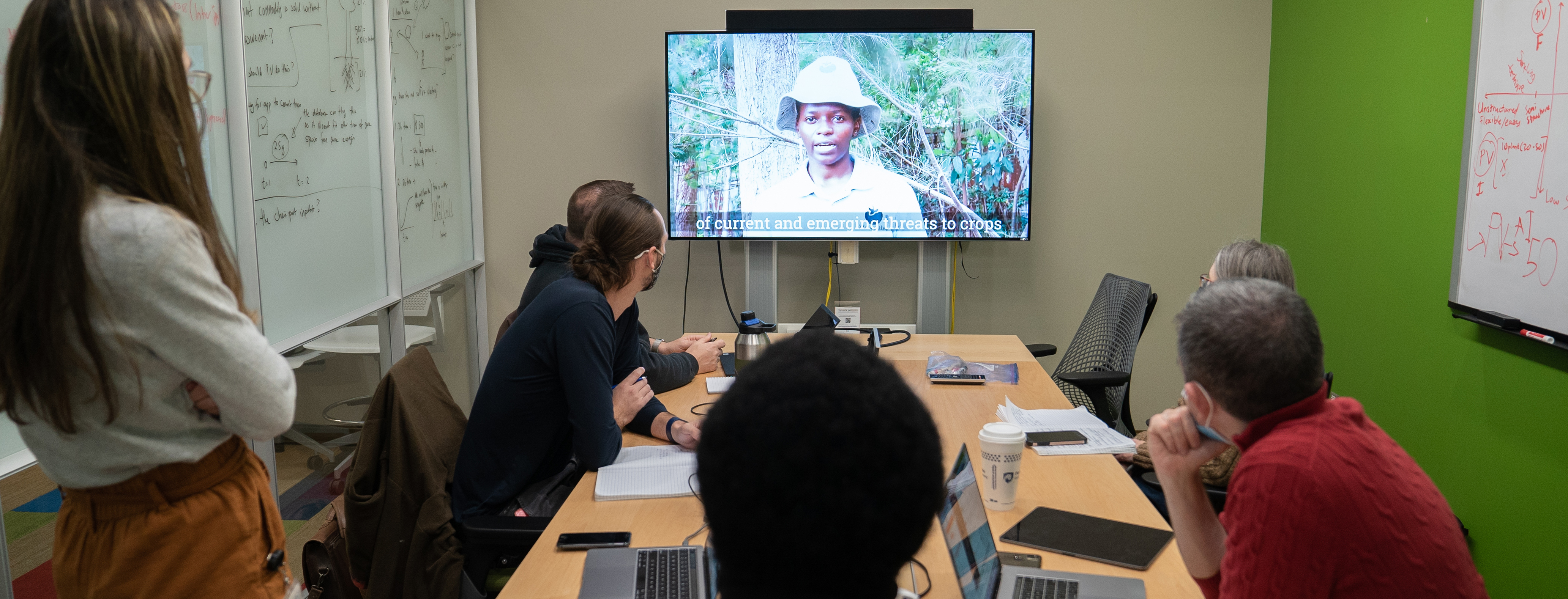 Scientists in conference room watching a video monitor